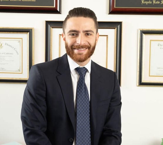Michael Saeedian sits at a desk in front of framed accomplishments