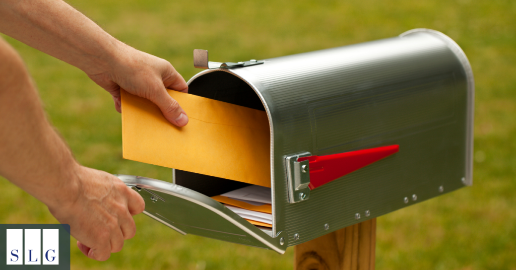 Person placing an envelope in a mailbox to illustrate sending a legal demand letter.