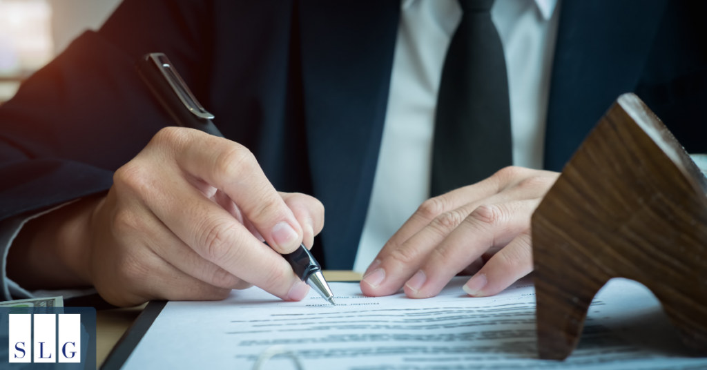 Signing a settlement document Man in a suit signing a legal document beside a wooden gavel