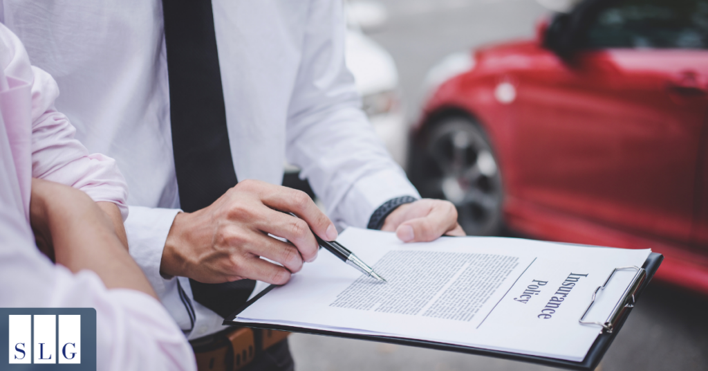 Reviewing an auto insurance policy Man reviewing an insurance policy on a clipboard with a driver outside