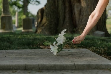 a woman puts a lily on a grave of someone who died a wrongful death