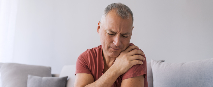 A man sitting at home with intense pain from a shoulder injury