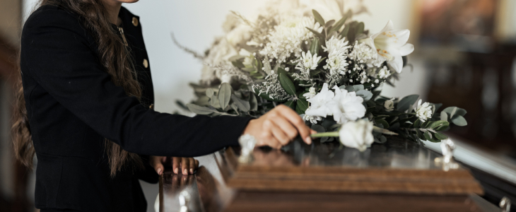 A person holding a casket with flowers on it