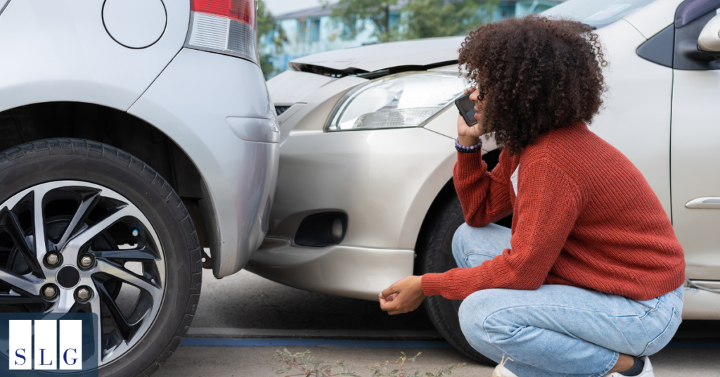 Driver documenting vehicle damage and accident scene after collision