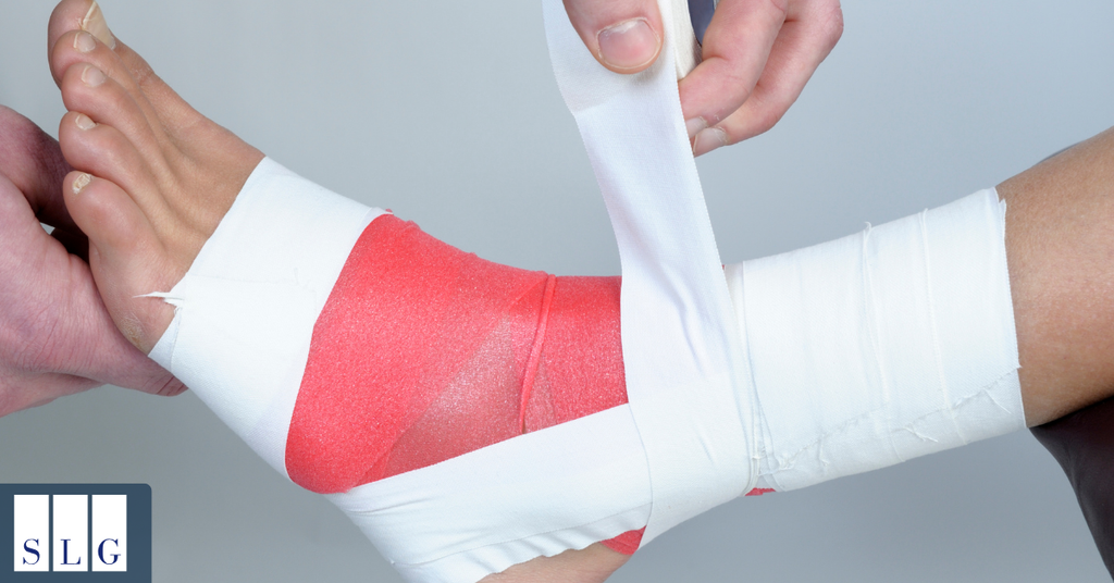 Medical professional wrapping an injured ankle with a supportive bandage during treatment.